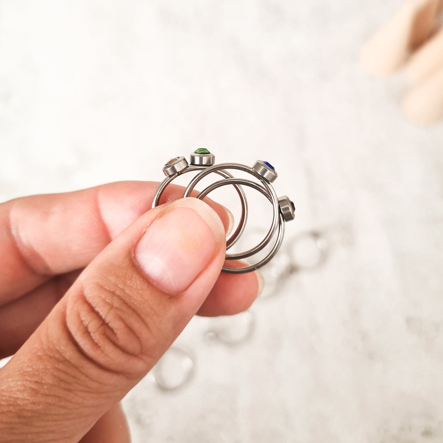 Side view of Stainless steel rings, each set with a coloured cubic zirconia birthstone representing the its month.