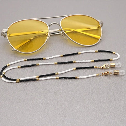 Black and white miyuki bead sunglass straps with gold accents.