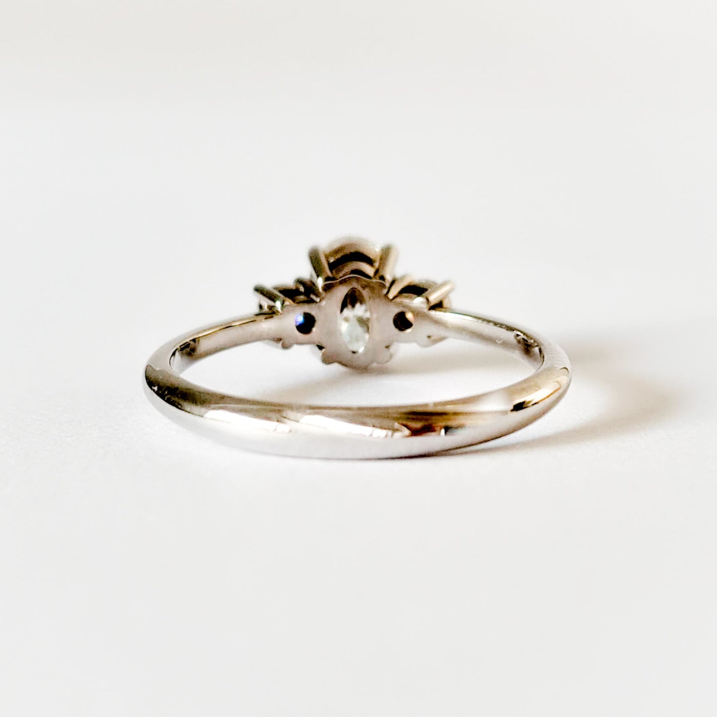 Oval and round cut moissanite three stone engagement ring in white gold, back view on white background