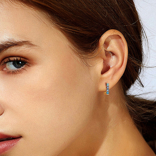 Close-up of a woman wearing colorful earrings with a neutral background