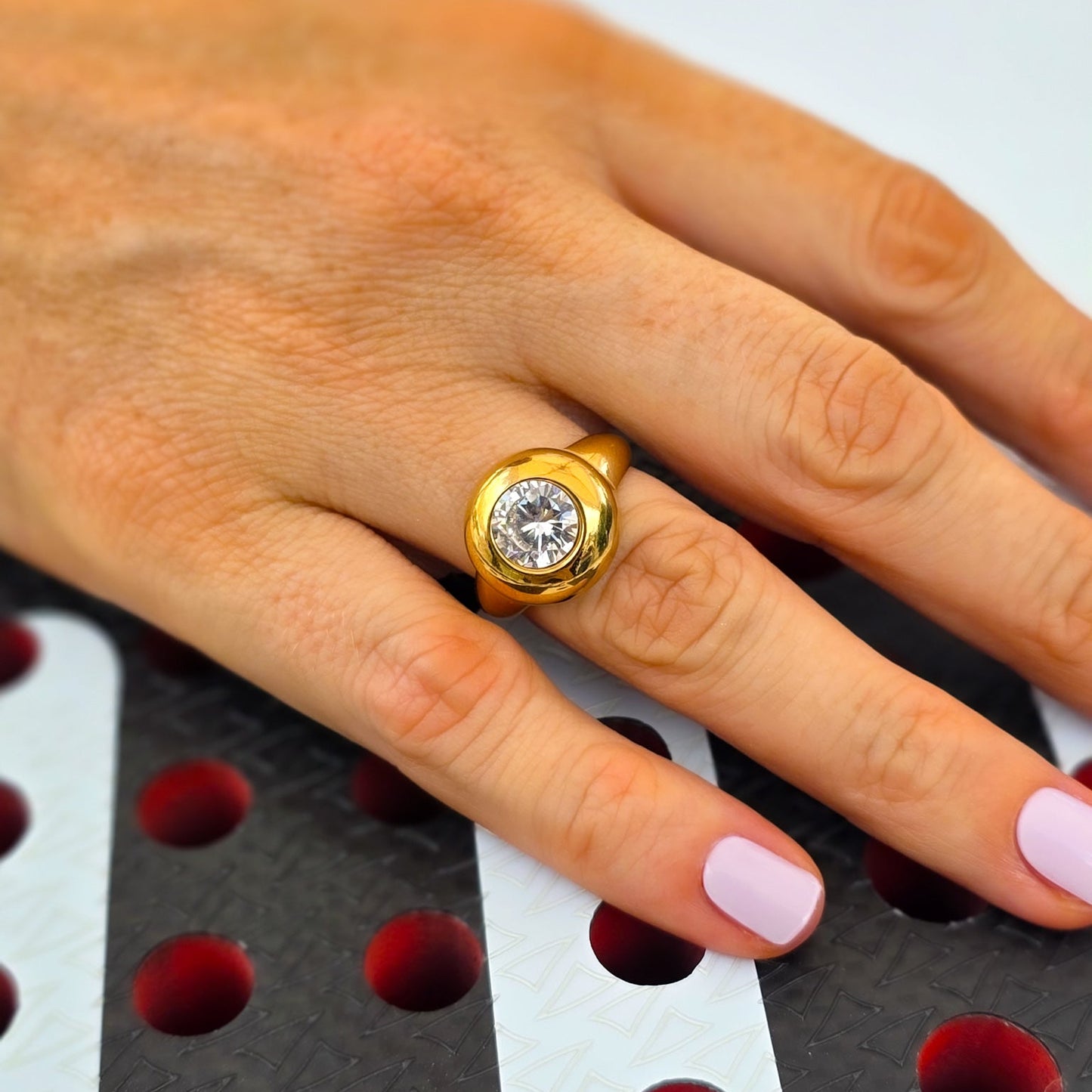 Gold ring with a diamond on a hand against a blurred background