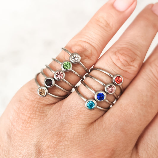 Stainless steel rings, each set with a coloured cubic zirconia birthstone representing the its month.