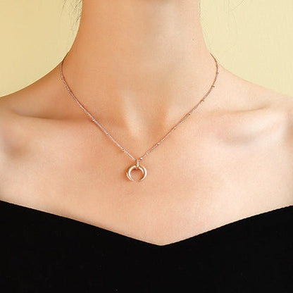 Rose gold plated steel minimalist crescent moon pendant on a ball chain necklace all made from durable titanium on woman's neck.