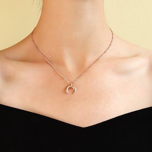 Rose gold plated steel minimalist crescent moon pendant on a ball chain necklace all made from durable titanium on woman's neck.