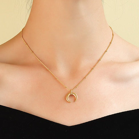 Yellow gold plated steel minimalist crescent moon pendant on a ball chain necklace all made from durable titanium on woman's neck