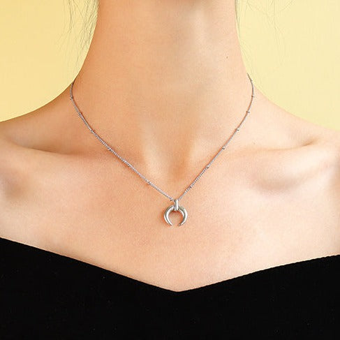 Minimalist crescent moon pendant on a ball chain necklace all made from durable titanium on woman's neck.